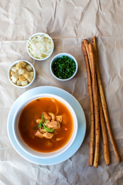 Vue de dessus de la soupe de fruits de mer servie avec des bâtonnets et des cubes de pain, du fromage râpé, des herbes