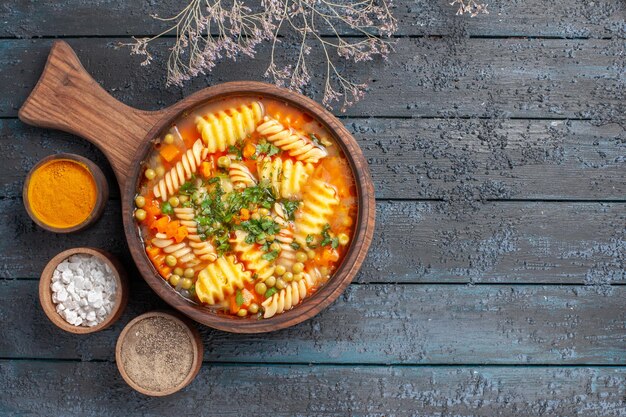 Vue de dessus soupe de pâtes en spirale délicieux repas avec différents assaisonnements sur le bureau sombre couleur soupe de pâtes italiennes cuisine plat