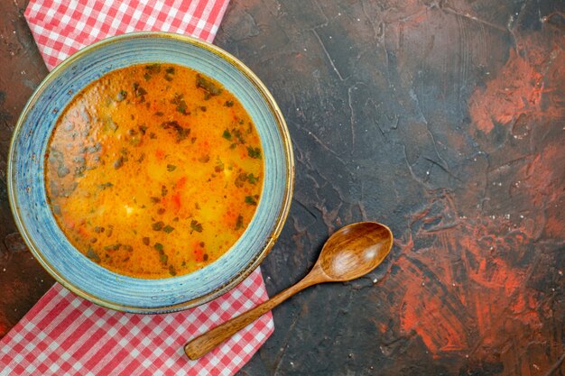 Vue de dessus de la soupe de riz dans un bol sur une nappe à carreaux blanc rouge cuillère en bois sur fond