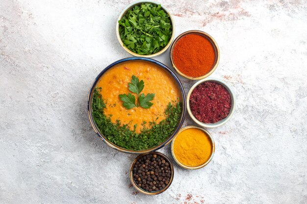 Vue de dessus soupe savoureuse avec différents assaisonnements et légumes verts sur une surface blanche