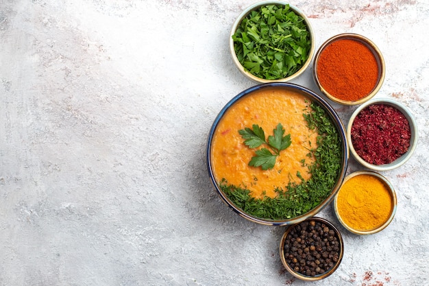 Vue de dessus soupe savoureuse avec différents assaisonnements sur la surface blanche des légumes de la soupe alimentaire repas