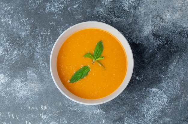 Photo gratuite vue de dessus de la soupe de tomates fraîches maison dans un bol blanc sur une table grise.