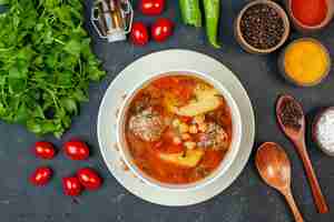 Photo gratuite vue de dessus d'une soupe de viande délicieuse avec des légumes verts et des assaisonnements sur fond sombre