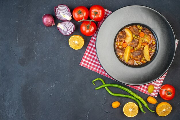 Vue de dessus soupe de viande avec garniture sur assiette ronde légumes frais sur table noire avec espace libre