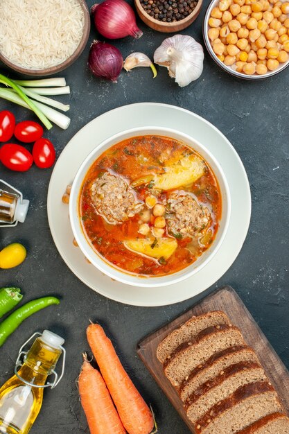 Vue de dessus de la soupe à la viande avec des miches de pain et des assaisonnements sur fond sombre