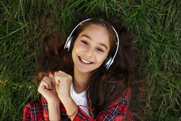 Vue de dessus de la souriante jeune fille brune allongée sur l'herbe