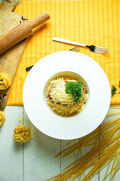 Vue de dessus de spaghetti bolognaise au parmesan dans un bol blanc sur jaune