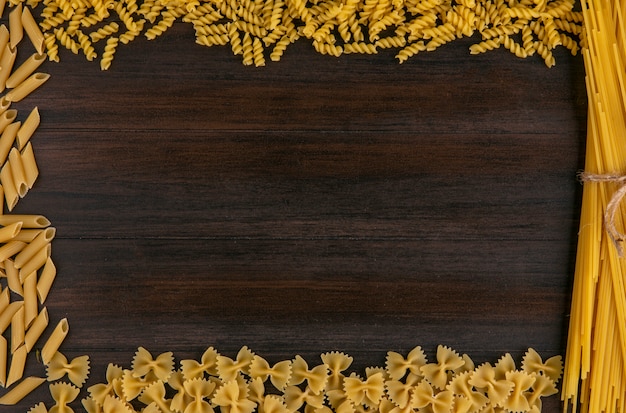 Photo gratuite vue de dessus des spaghettis crus avec des pâtes sur une surface en bois