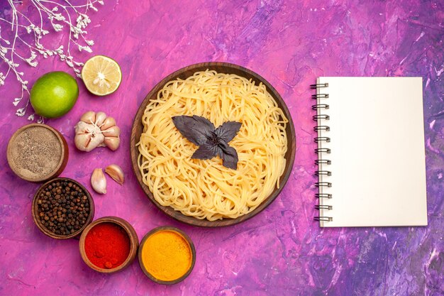 Vue de dessus des spaghettis cuits avec des assaisonnements sur un plat de pâtes de repas de pâte de table rose