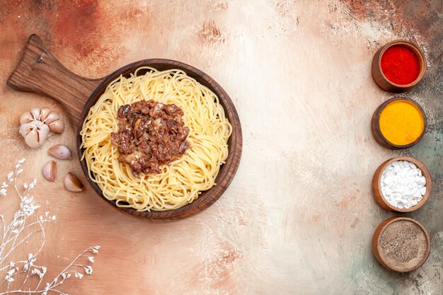 Vue de dessus des spaghettis cuits avec de la viande hachée sur un plat de bureau en bois assaisonnement de pâte de pâtes