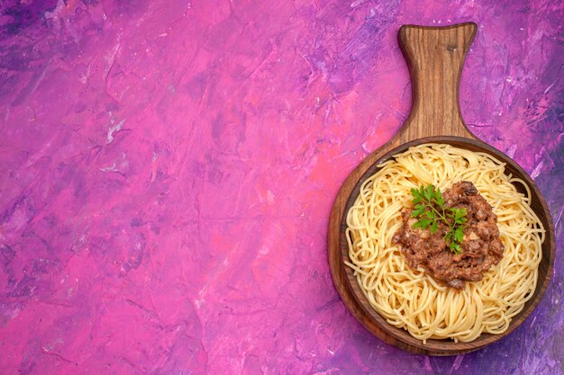 Vue de dessus des spaghettis cuits avec de la viande hachée sur un plat de pâte d'assaisonnements pour pâtes de table rose