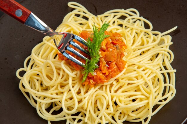 Vue de dessus des spaghettis avec sauce sur une fourchette à assiette sur un tableau noir