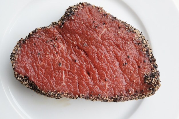 Vue de dessus d'un steak cru assaisonné sur une assiette sur la table