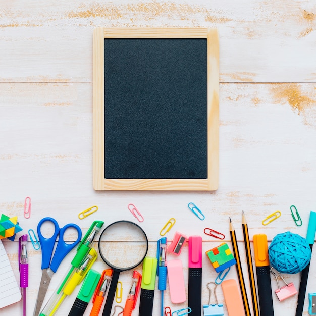 Photo gratuite vue de dessus d'un tableau noir avec des fournitures scolaires sur fond blanc