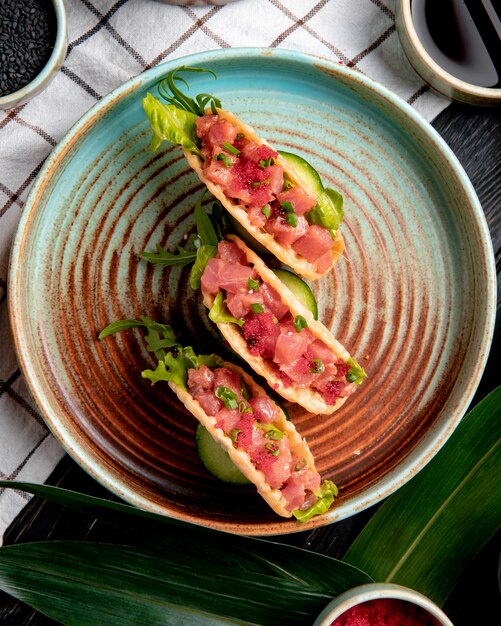 Vue de dessus des tacos au saumon au caviar rouge et oignon vert sur une assiette sur une nappe à carreaux