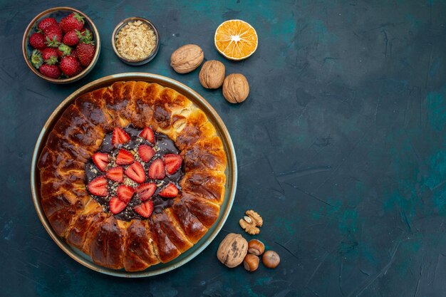 Vue de dessus de la tarte aux fraises avec bloc-notes sur la surface bleue