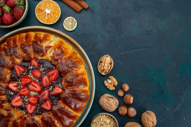 Vue de dessus de la tarte aux fraises avec des noix et de la cannelle sur un bureau bleu