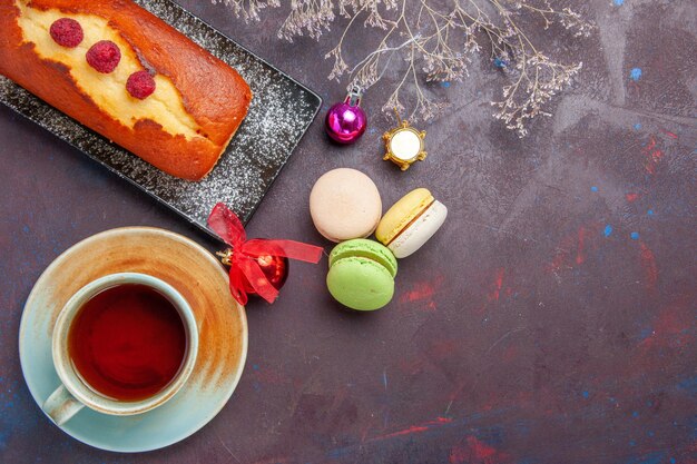 Vue de dessus tarte délicieuse avec une tasse de thé et des macarons sur une surface sombre gâteau au sucre tarte aux biscuits thé aux biscuits sucrés