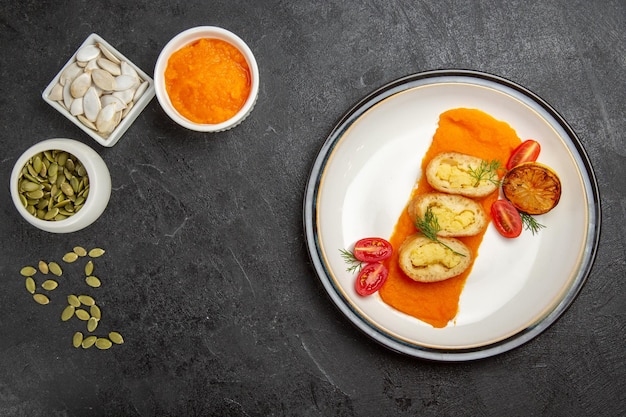 Vue de dessus des tartes aux pommes de terre avec de la citrouille en purée et ses graines sur fond gris foncé cuire une tarte aux couleurs du gâteau au four