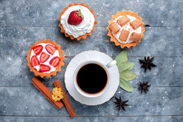 Vue de dessus de la tasse de café chaud et fort avec des gâteaux et de la cannelle sur gris, boisson sucrée de bonbons au café