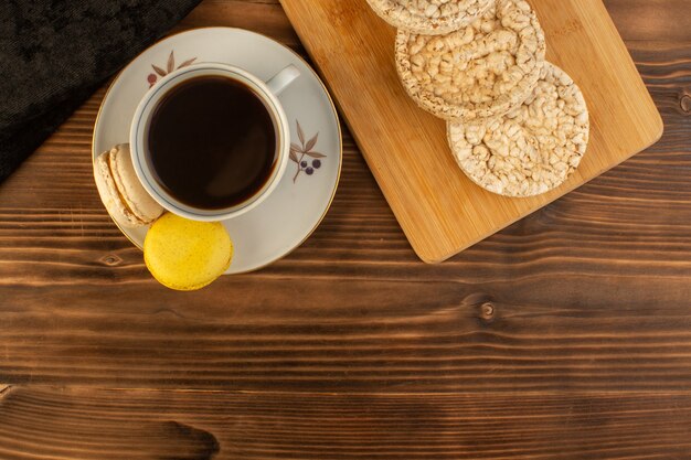 Une vue de dessus tasse de café chaud et fort avec des macarons français et des craquelins sur la table rustique en bois brun café boisson chaude