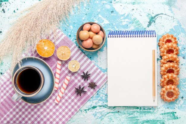 Vue de dessus tasse de café avec des cookies et bloc-notes sur fond bleu clair gâteau cuire biscuit tarte au sucre sucré