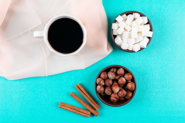 Vue de dessus tasse à café avec des morceaux de sucre cannelle et noix sur la surface verte