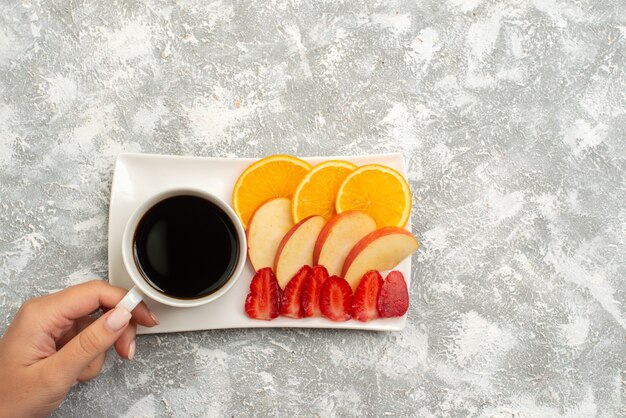 Vue de dessus tasse de café avec des pommes tranchées oranges et fraises sur fond blanc fruits frais moelleux