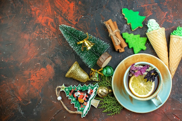 Vue De Dessus Tasse De Glaces Au Thé Bâtons De Cannelle Biscuits D'arbre De Noël Ornements De Noël Sur Table Rouge Foncé