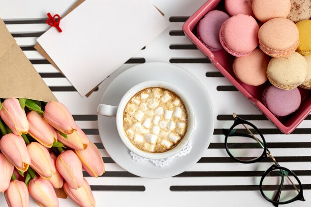 Vue de dessus de tasse de guimauves avec tulipes et macarons