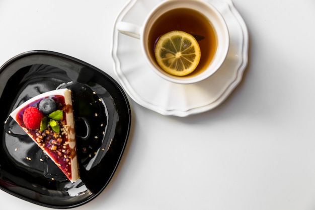 Photo gratuite une vue de dessus de la tasse de thé au citron et tranche de gâteau sur fond blanc