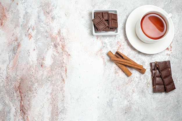 Vue de dessus de la tasse de thé avec des barres de chocolat sur une surface blanche