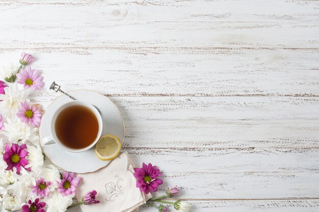 Une vue de dessus de la tasse de thé à base de plantes avec des fleurs sur fond texturé en bois peint