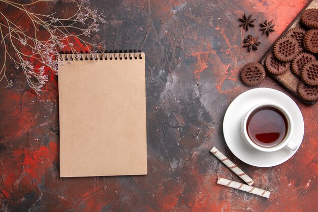 Vue de dessus tasse de thé avec des biscuits au chocolat sur la table noire biscuit thé biscuit