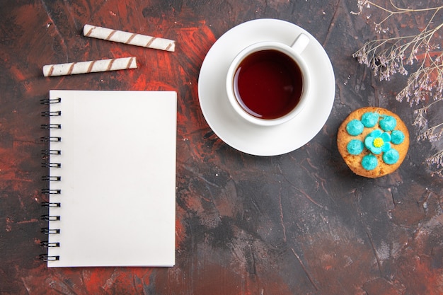 Vue de dessus tasse de thé avec des biscuits et le bloc-notes sur la table sombre biscuit bonbon biscuit sucré