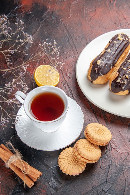 Vue de dessus tasse de thé avec des biscuits et des éclairs sur la table noire biscuit thé au sucre sucré