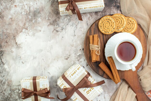 Vue de dessus tasse de thé avec des biscuits sucrés et des cadeaux sur fond clair cérémonie des biscuits couleur tarte au café au sucre