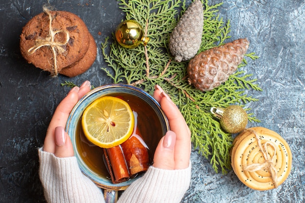 Photo gratuite vue de dessus tasse de thé avec des biscuits sucrés et des cônes sur fond sombre clair