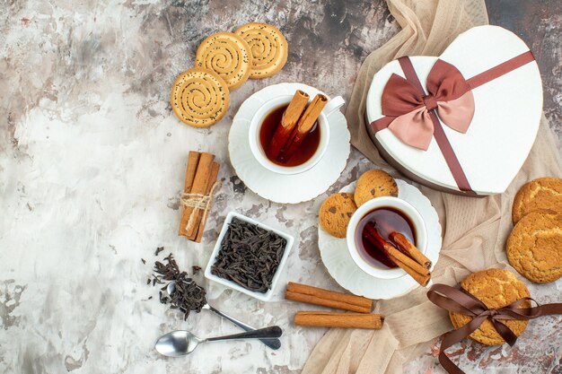 Vue de dessus tasse de thé avec des biscuits sucrés sur fond clair pause café biscuit tarte cérémonie cannelle