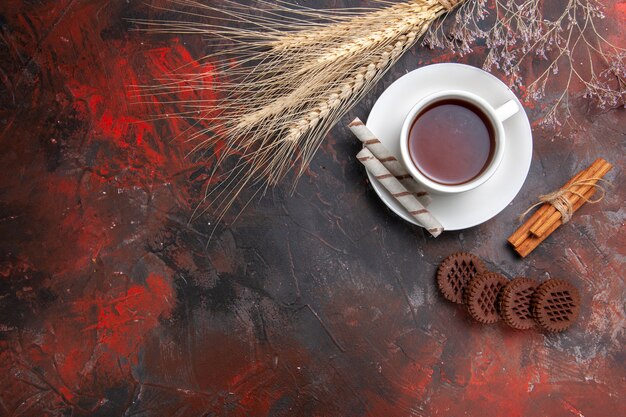 Vue de dessus tasse de thé avec des biscuits sucrés sur table sombre