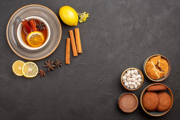 Vue de dessus tasse de thé avec des biscuits sur une surface sombre biscuit aux fruits du thé sucré