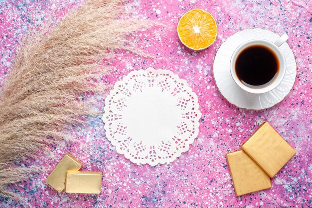 Vue de dessus de la tasse de thé avec des bonbons au chocolat sur une surface rose