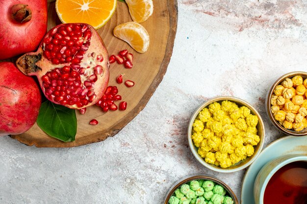 Vue de dessus tasse de thé avec des bonbons au sucre et des fruits sur un espace blanc