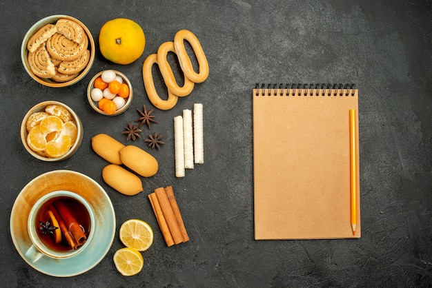 Vue de dessus tasse de thé avec des bonbons biscuits et fruits sur table grise thé biscuits sucrés