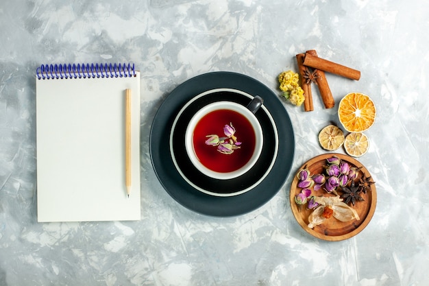 Vue de dessus tasse de thé avec de la cannelle et des fleurs sur un bureau blanc thé fleur de boisson sucrée