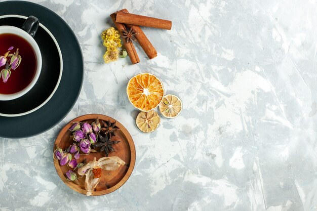 Vue de dessus tasse de thé avec de la cannelle et des fleurs sur la fleur de boisson sucrée de thé de surface blanc clair