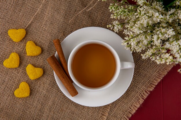 Vue de dessus d'une tasse de thé à la cannelle et de fleurs sur une serviette beige