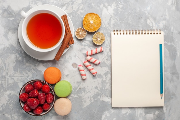 Vue de dessus tasse de thé à la cannelle et macarons français sur surface blanche