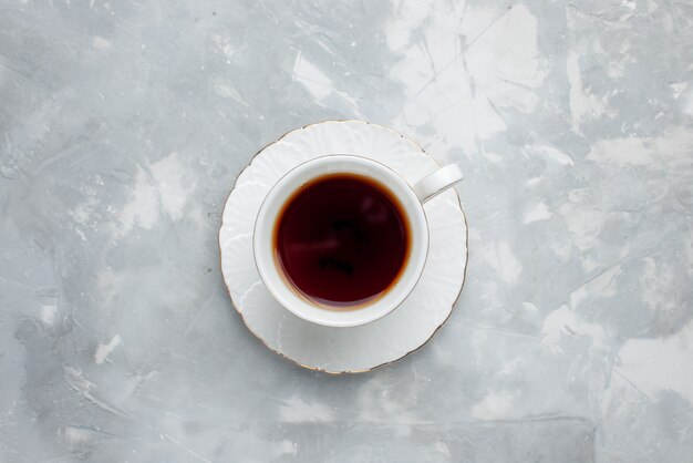 Vue de dessus de la tasse de thé chaud à l'intérieur de la tasse blanche sur la lumière, boire du thé sucré