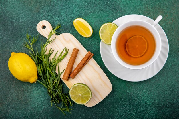 Vue de dessus d'une tasse de thé avec des citrons et des bâtons de cannelle sur planche de cuisine en bois sur gre